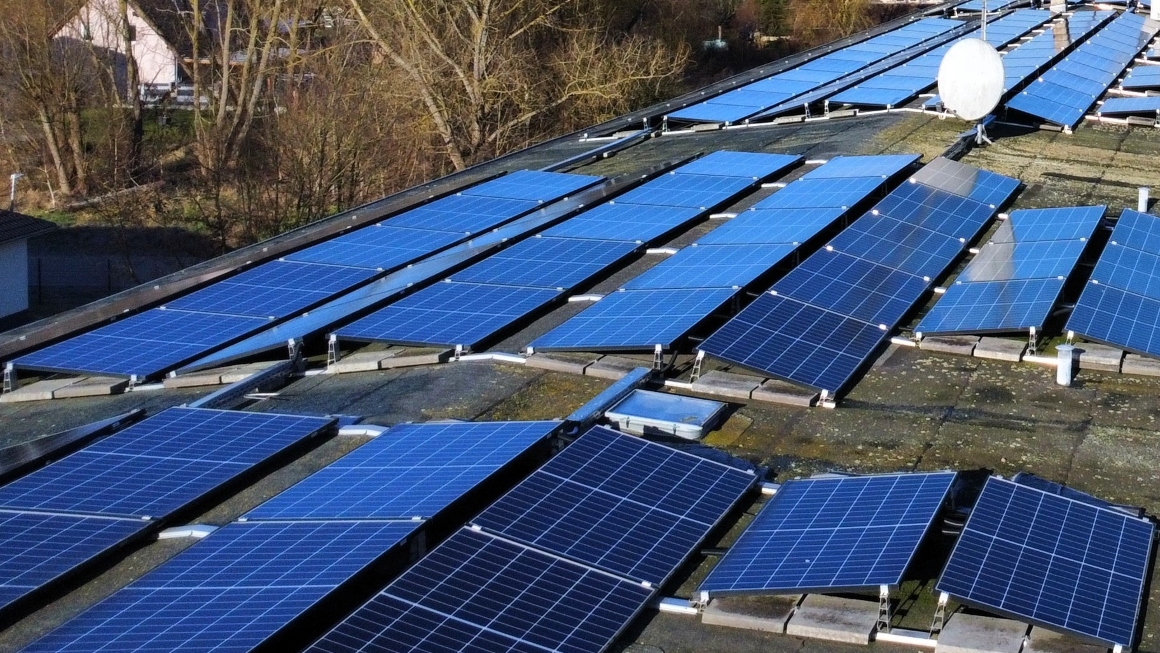 hotovoltaik-Anlage auf einem Flachdach eines Mehrfamilienhauses mit zahlreichen Solarmodulen und Satellitenschüssel