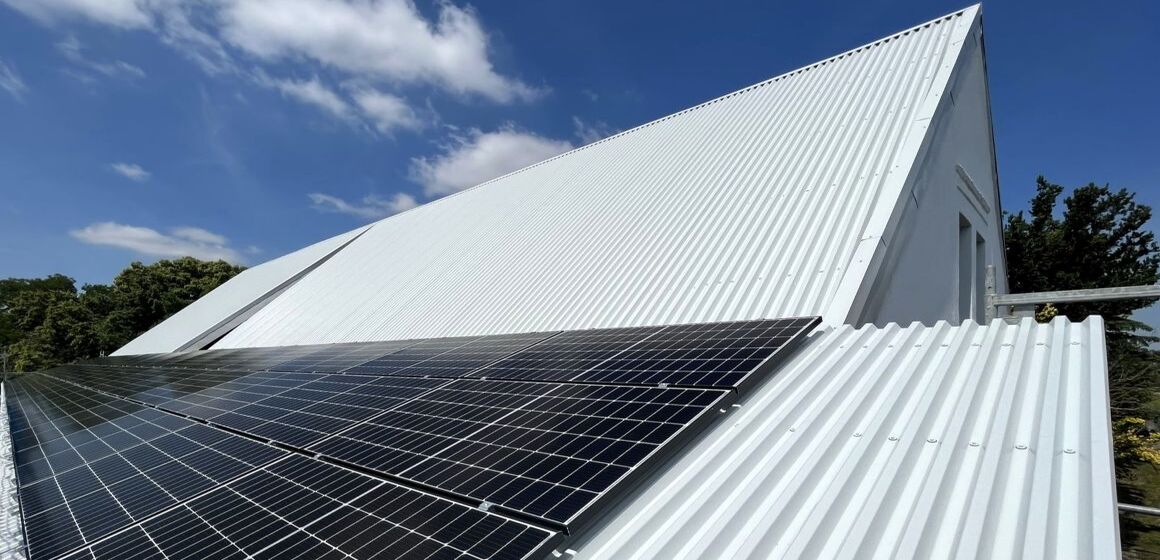 Moderne Photovoltaik-Anlage auf einem weißen Einfamilienhaus mit Wellblechdach bei sonnigem Wetter
