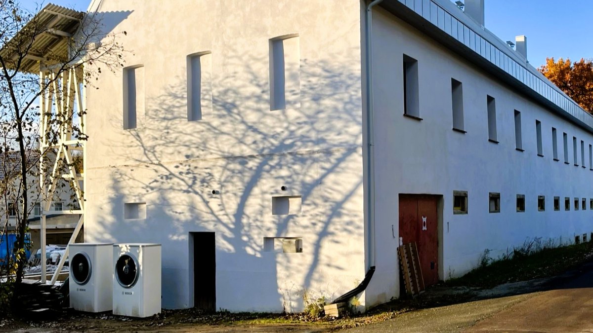 Zwei Außengeräte einer Luft-Wasser-Wärmepumpe vor einem sanierten Bestandsgebäude zur nachhaltigen Wärmeversorgung